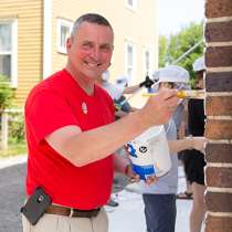 Valu Home Centers photo of: John, Valu Crew Volunteer, helps teach community members about exterior painting while removing graffiti